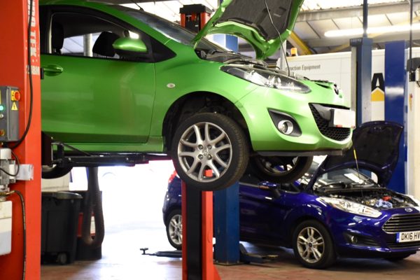 A car raised on a lift in the MOT bay