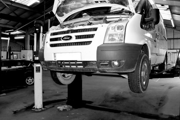 A Ford Transit van raised on a ramp in the workshop