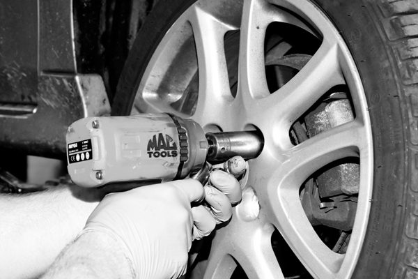 A mechanic fitting a wheel with an air gun